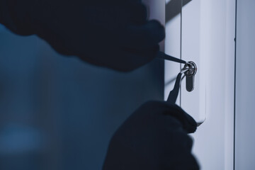 Forced Entry. Closeup of unrecognizable intruder in black gloves unlocking door with master key