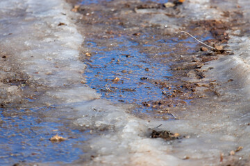 A puddle forming in driveway from the melting snow