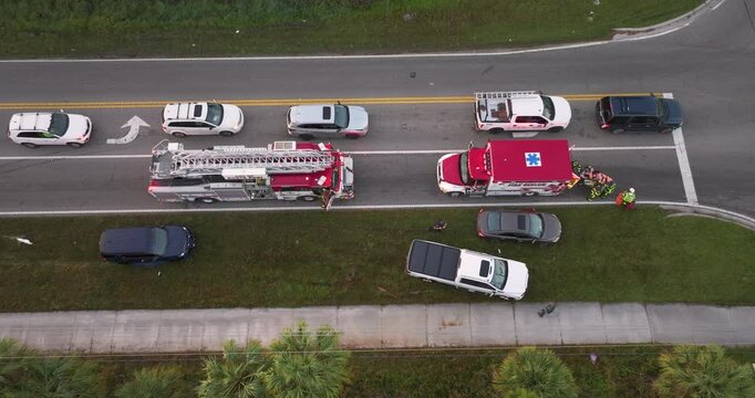 First responders responding to car accident site on American street. Emergency services helping victims of vehicle crash on road in USA.