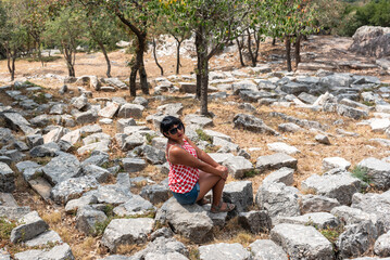 Fototapeta premium Tourist red polka dots shirt posing in the surroundings of Temple of Apollo Epicurius at Bassae of Phigaleia, where stone blocks and material for the construction of the temple is located