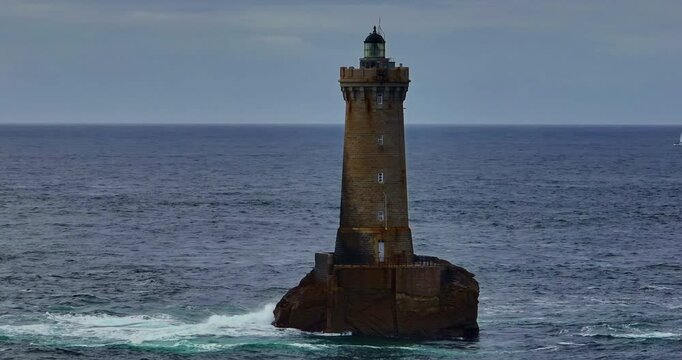 A rotating overhead shot of Phare du Four a lighthouse in Bretagne France. An ancient one standing far from the shore in the ocean and the first to meet huge waves