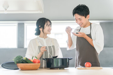 料理を作って味見をする夫婦・カップル・男女（キッチン）
