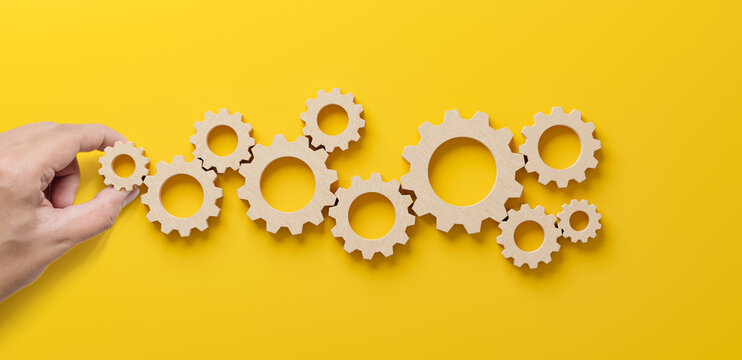 Business process and workflow automation with flowchart. Hand holding wooden cog flowing process management on yellow background - Powered by Adobe
