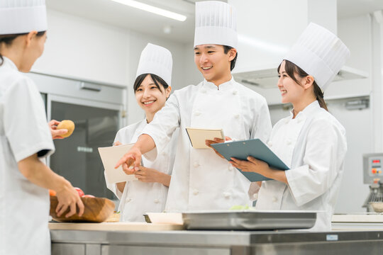 調理師のセミナー・専門学校・社員教育で教える講師の女性と生徒の男女（外食産業）
