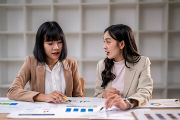 Fototapeta premium Two women are sitting at a table with papers in front of them