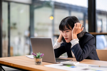 A woman is sitting at a desk with a laptop open in front of her