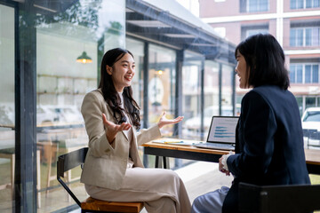 Two women are sitting at a table in a restaurant, one of them is smiling