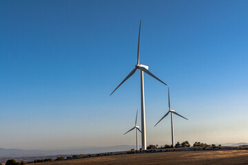 Wind turbines on a rural hill with clear sky