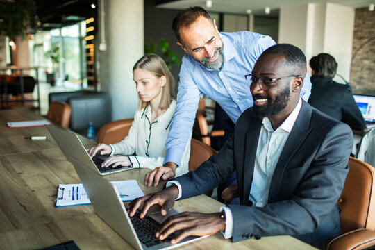 Business professionals discussing document with a colleague in modern office