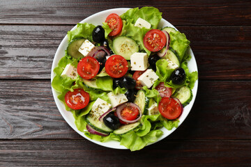 Delicious fresh Greek salad on wooden table, top view