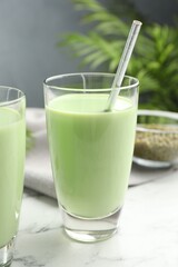 Fresh mung bean juice in glasses on white marble table, closeup