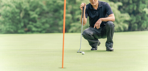 ゴルフ場のグリーン上でラインを読む男性ゴルファー
