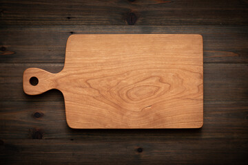 Handmade cherry wood chopping board on old wooden table. wooden chopping board