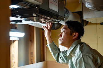 ダクトを点検する作業着を着た男性