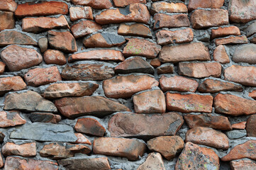 Closeup of old weathered brown stone wall, made of rough flat stones