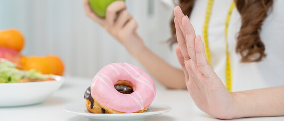 Diet and dieting. Beauty slim female body confuse donut. Woman in exercise clothes achieves weight loss goal for healthy life, crazy about thinness, thin waist, nutritionist.