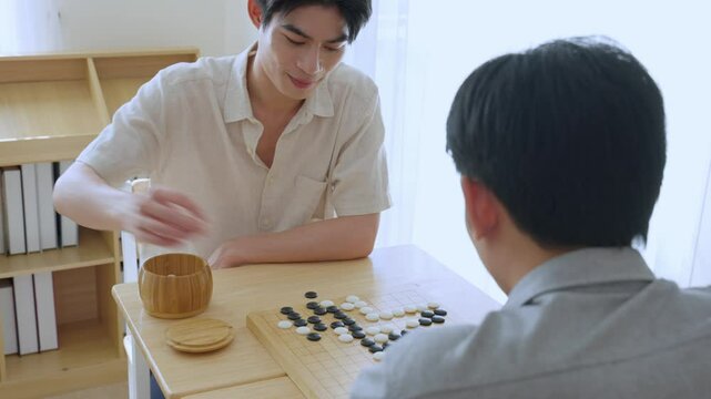 Asian young men playing board game Go during competition in community. 