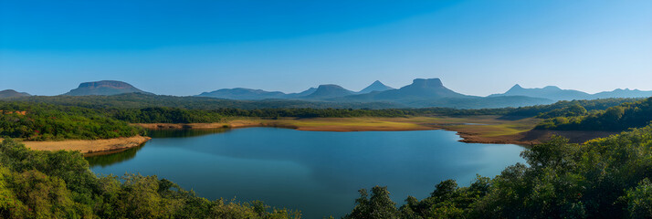 Obraz premium Serenity of a Sprawling Reservoir Encircled by Lush Greenery and Majestic Mountains Amidst a Clear Sky