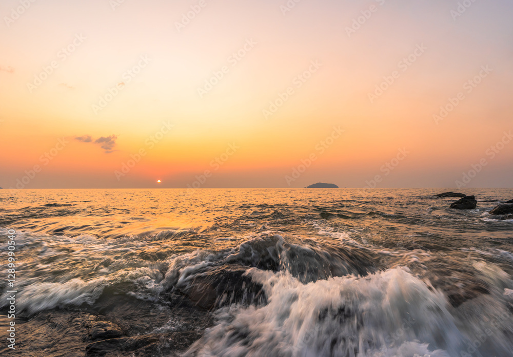 Wall mural sunset sky over beach seaside in the evening with long exposure white wave on top rock sea in golden
