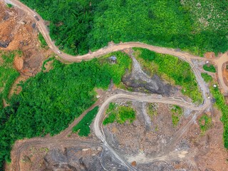 Aerial view of a hilly mining site where lush greenery is fading due to extensive stone mining,...