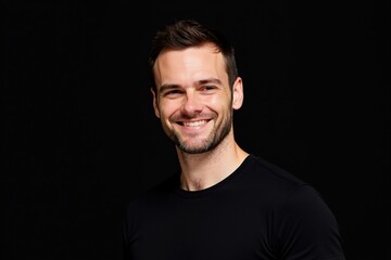 Obraz premium Smiling Young Adult Caucasian Male Wearing Black T-Shirt Posing Against a Dark Background with a Bright Smile, Reflecting Confidence and Approachability