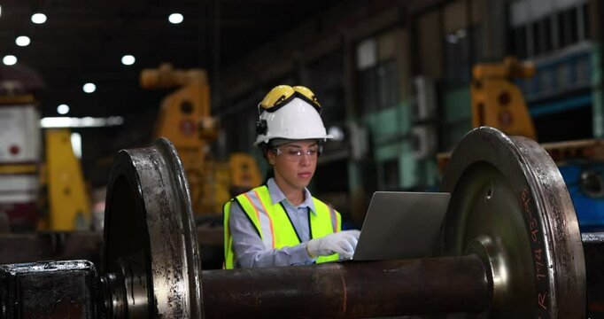 Female mechanic engineer or rail engineer with full PPE work with laptop at train garage