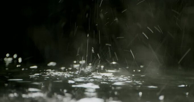 4K high-speed heavy tropical rainstorm on a black puddle floor, dynamic raindrops splashing. High-end cinematic rain closeup VFX insert, powerful weather element showcases the intense realism of rain.
