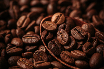 Wooden spoon on the roasted coffee beans on the wooden table. Warm colors background with coffee beans. Selective focus. Shallow depth of field.