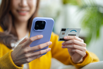 young asian woman smiling happy holding smartphone and credit card at home.asian female online banking transaction,E commerce virtual shopping,secure mobile banking,Pay for goods concept.