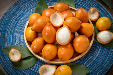 Achacha fruit or garcinia intermedia in wooden bowl on wooden background, Yellow Madrono Fruit or Lemon drop mangosteen in wooden basket on wooden texture background.