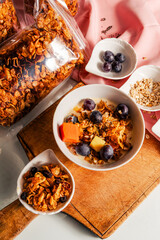 Healthy breakfast with yogurt mixed with homemade granola and fruits: mango, papaya and grapes.