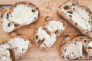 crusty bread slices with butter on cutting board shot from above