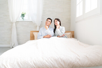 Fototapeta premium 起きてベッドの上で会話をする夫婦