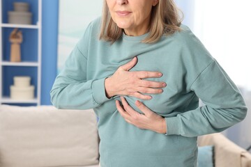 Heart attack. Senior woman suffering from pain in chest indoors, closeup
