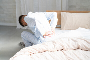 起きてベッドの上で腰を押さえている男性