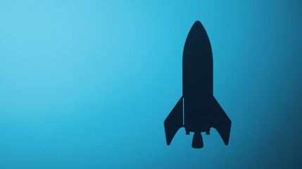 Fototapeta premium Rocket silhouette ascending on a gradient blue background, symbolizing rapid business growth and innovation. 