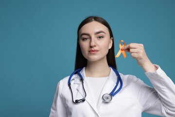 Multiple Sclerosis awareness. Doctor holding orange ribbon on light blue background