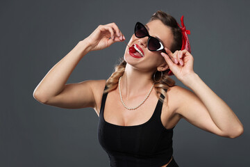 Beautiful woman eating cherry on grey background. Pin-up vibes