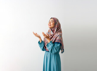 Beautiful young Asian Muslim woman wearing hijab praying with open arms, asking for prayer about something isolated on white background. People religious lifestyle concept 