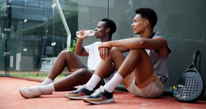Tennis, sports or men with break on court for resting, drinking water or match practice fatigue. Padel, friend or relax at fitness training for tournament recovery, workout burnout or tired on ground - Powered by Adobe