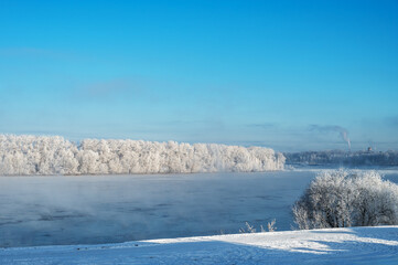 Winter morning landscape with river, water, forest and steam on the water.