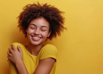 Happy woman hugging herself, yellow background, studio shot, self-love concept