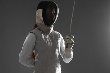 Fencer with epee on gray background. Combat sport