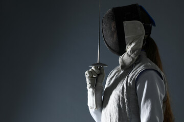 Fencer with epee on gray background, space for text