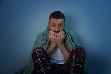 Fear of darkness. Scared man with blanket on light grey background
