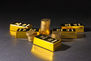 Gold bars and coins on black table, closeup