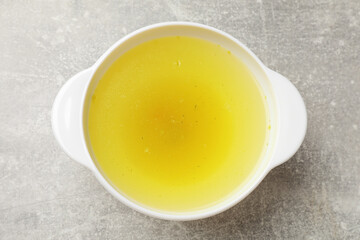 Tasty chicken bouillon in bowl on grey table, top view