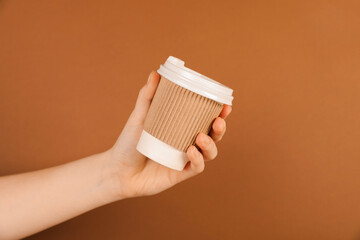 Woman holding paper cup on brown background, closeup. Mockup for design