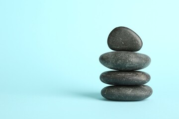 Stack of rocks on light blue background, space for text. Harmony and life balance