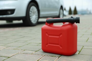 Red plastic canister with spout on pavement outdoors